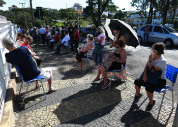 Idosos aguardam sentados na calçada para tomarem a vacina, no posto montado na Casa da Criança Paralítica. 
Foto: Leandro Ferreira/Hora Campinas