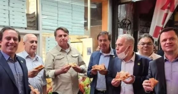 Bolsonaro, Queiroga e demais membros da comitiva brasileira comem pizza na rua diante de uma lanchonete: imagem viralizou Foto: Redes sociais