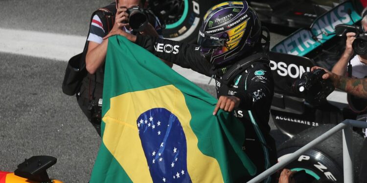 O piloto Lewis Hamilton carrega bandeira brasileira ao final da corrido em São Paulo. Foto: Agência Brasil