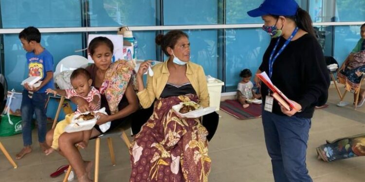 Funcionária da organização fala com pessoas desalojadas pelas enchentes no Timor -Leste - Foto: OIM