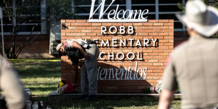 Policial deixa flores em frente à escola onde ocorreu o massacre. Foto: Reprodução
