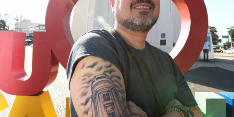 Gustavo Prado, a tatuagem, o totem e a Torre do Castelo ao fundo: gratidão Foto: Divulgação