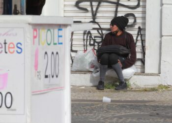 Mulher tenta se esconder do frio, perto de uma placa de venda de picolés. Fotos: Leandro Ferreira/Hora Campinas
