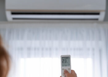 Jovem usa controle remoto para abaixar temperatura do ar-condicionado e suportar o calorão - Foto: Freepik/Divulgação