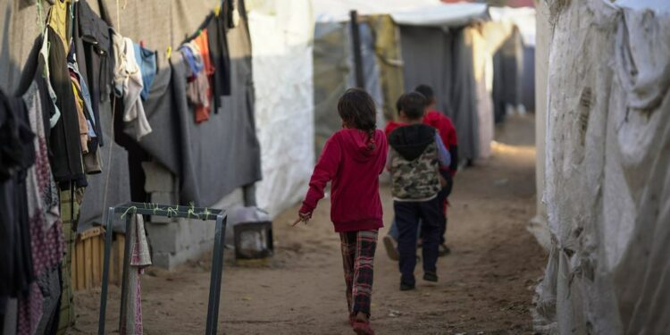 Crianças caminham por um acampamento temporário no sul de Gaza. Foto: OMS