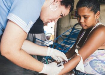 Um profissional de saúde coleta amostras de sangue de uma mulher que já havia contraído dengue. Foto: Opas/Joshua E. Cogan