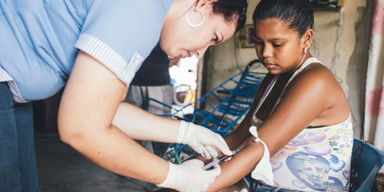 Um profissional de saúde coleta amostras de sangue de uma mulher que já havia contraído dengue. Foto: Opas/Joshua E. Cogan